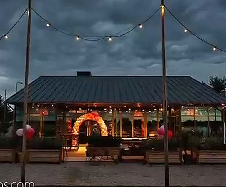 Feestlocatie in de avond met een verlichte ballonboog